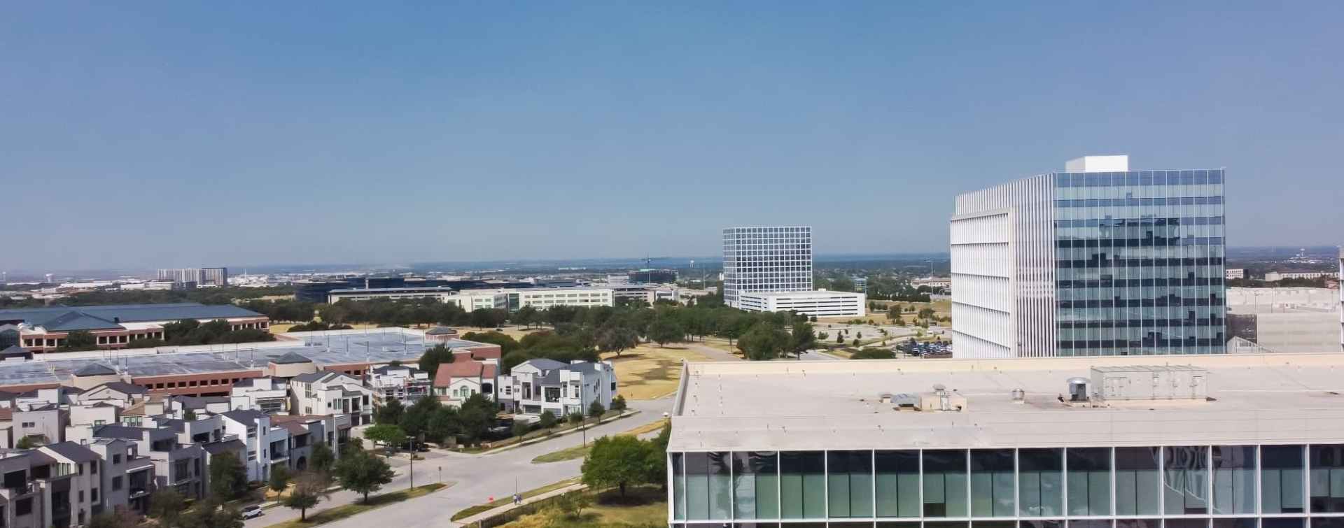 panoramic view of Plano office space buildings in the foreground and nearby residential villas in the background